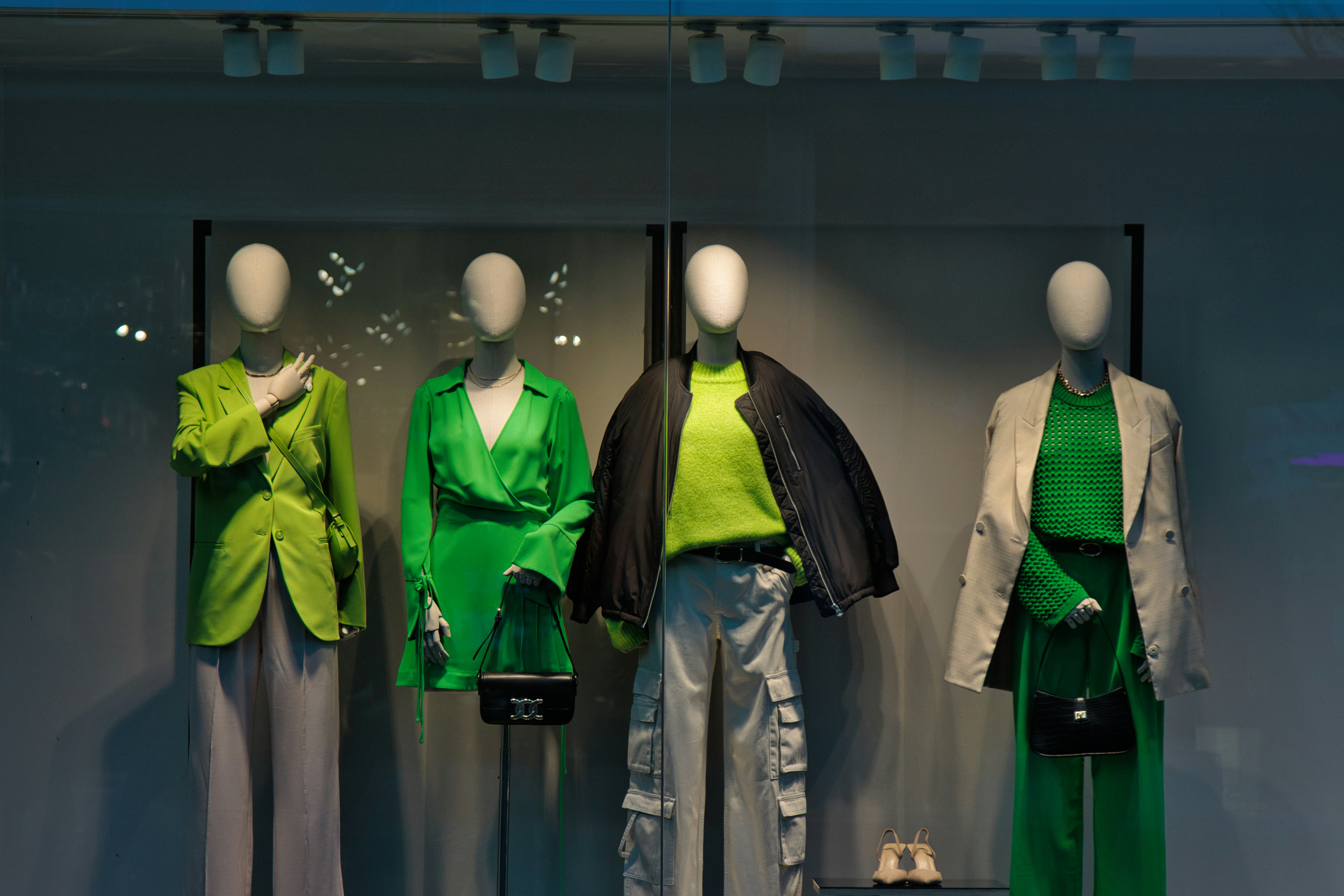 A group of mannequins dressed in green and grey showcasing sustainable fashion materials